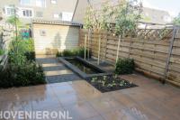 Achtertuin met sierbestrating, vijver en leibomen