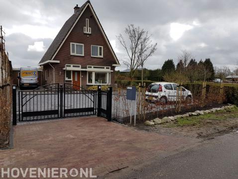 Voortuin met sierpoort en oprit van grind