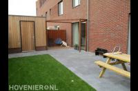 Achtertuin met bestrating, kunstgras en houten pergola
