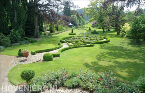 Ruime klassieke tuin met gazon en vormsnoei van buxus