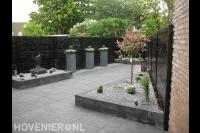 Strakke onderhoudsarme tuin met donkere schutting en bestrating 2
