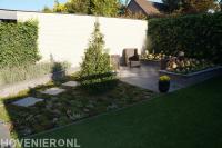 Tuin met gazon, plantenbak en zithoek met schaakbord motief