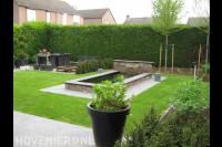 Achtertuin met gazon en vijver met watermuur