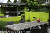 Kleurrijke tuin met vijver en terrasoverkapping met loungeset
