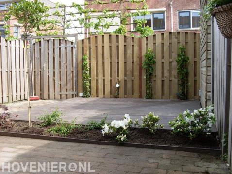 Tuin met vlonder en houten schutting met poort