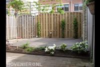 Tuin met vlonder en houten schutting met poort