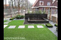 Tuinaanleg met vijver, kunstgras en hedera schutting van betongaas