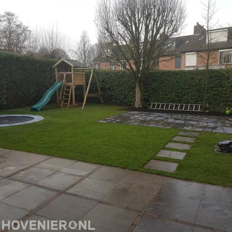 Kindvriendelijke tuin met terras, gazon, trampoline en speeltoestel