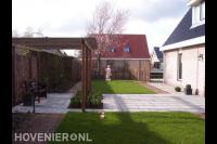 Tuin met houten pergola boven terras en gazon