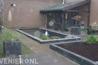 Achtertuin met overkapping en strakke vijver met fontein