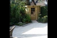 Tuin met lichtgrijze bestrating en houten tuinhuis