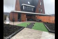 Tuinaanleg met natuursteen tegels, kunstgras en buitenverlichting