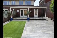 Achtertuin met terrasoverkapping, sierbestrating en kunstgras