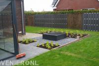 Tuinaanleg met sierbestrating, gazon, waterornament en schutting