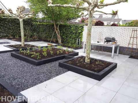 Moderne achtertuin met grote tegels, kiezels en plantenbakken