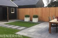 Tuinaanleg met natuursteen tegels, graszoden en houten schutting