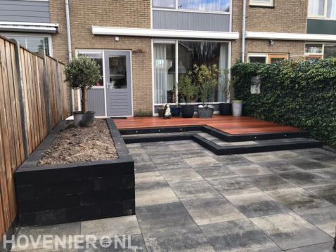 Tuinaanleg met houten vlonder en bestrating van natuursteen