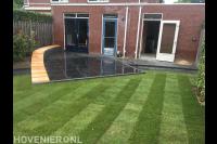 Achtertuin met gazon van graszoden, terras en maatwerk bankje