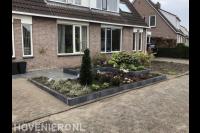 Voortuin met bestrating en verhoogde borders met nieuwe beplanting