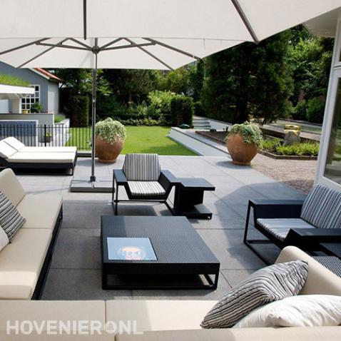 Modern terras met grote tegels, loungebanken en parasols