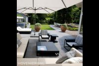Modern terras met grote tegels, loungebanken en parasols