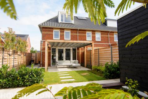 Tuinaanleg met terras, gazon, leibomen en pergola met schaduwdoek