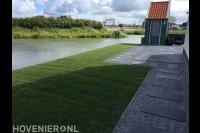 Tuin aan het water met gazon en sierbestrating