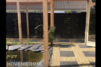 Tuin met vijver, houten pergola en schutting met klimplanten