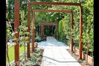 Houten pergola's over tuinpad van betontegels