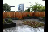 Hardhouten schutting, verhoogde borders en bestrating van natuursteen