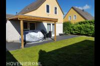 Tuinaanleg met gazon van graszoden en houten overkapping