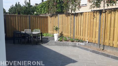 Strakke tuin met bestrating van natuursteen en hout beton schutting