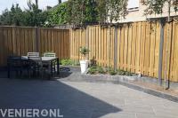 Strakke tuin met bestrating van natuursteen en hout beton schutting