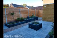 Tuinaanleg met plantenbakken en bestrating van natuursteen en klinkers