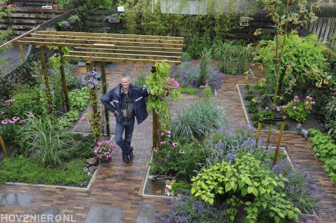 Groene tuin met pergola, bestrating en kleurrijke beplanting