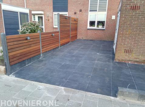 Tuin met bestrating van betontegels en houten schutting