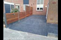 Tuin met bestrating van betontegels en houten schutting