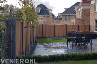 Achtertuin met bestrating, kunstgras en hout beton schutting