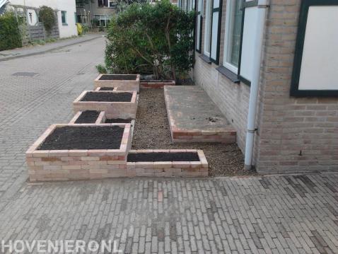 Kleine voortuin met plantenbakken van gebakken stenen