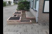 Kleine voortuin met plantenbakken van gebakken stenen