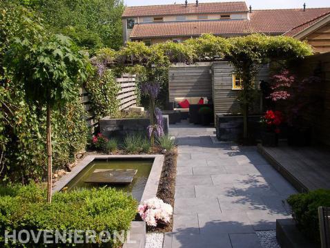 Achtertuin met kleine vijver en pergola met klimplanten 1