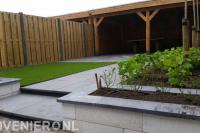 Tuin met kunstgras, hout beton schutting en houten overkapping