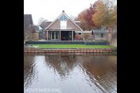 Tuin aan het water met beschoeiing, kunstgras en verhoogd terras