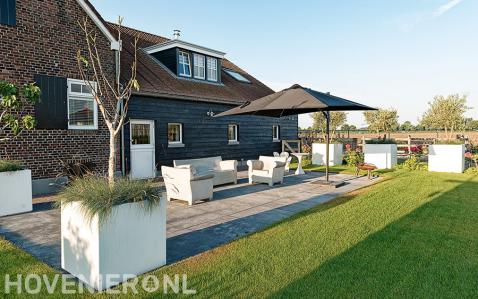 Terras van grote tegels en witte bloembakken bij boerderij