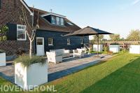 Terras van grote tegels en witte bloembakken bij boerderij