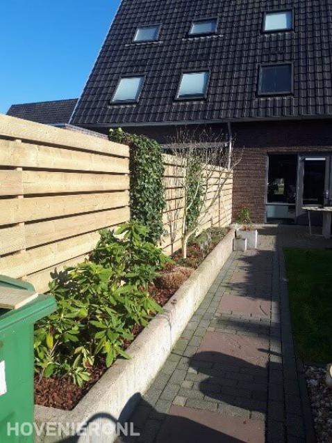 Houten schutting met stenen plantenbakken