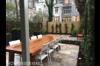 Tuin met terras van natuurstenen tegels en bloembakken met buxusbollen