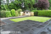 Achtertuin met kunstgras en bestrating van grote antraciet tegels