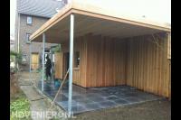 Houten schuurtje met overkapping en bestrating