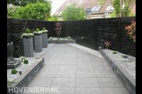 Strakke onderhoudsarme tuin met donkere schutting en bestrating 1